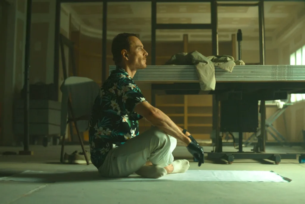 Crítica de The Killer de David Fincher - El personaje de MIchael Fassbender espera sentado.