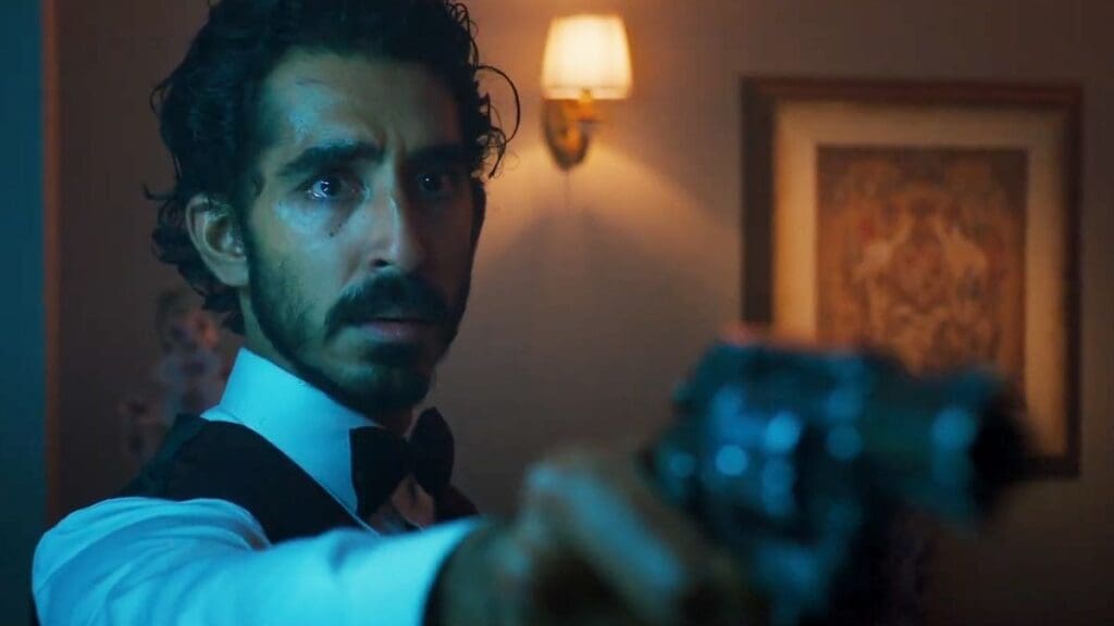 Dev Patel sosteniendo una pistola