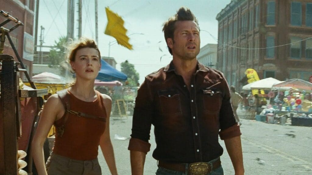 crítica de tornados - Glen Powell y Daisy Edgar-Jones miran un tornado