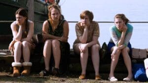 Escena de Girls con Jessa, Shoshanna, Hannah y Marnie en un muelle, reflejando un momento de tensión en la serie de Max