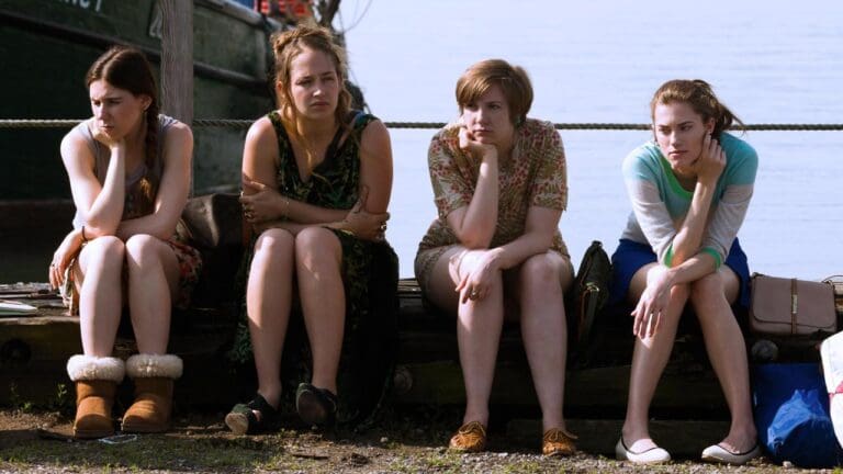 Escena de Girls con Jessa, Shoshanna, Hannah y Marnie en un muelle, reflejando un momento de tensión en la serie de Max