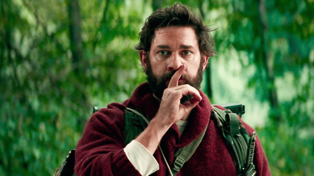 John Krasinski en A Quiet Place (2018), haciendo la señal de silencio en una escena clave del thriller postapocalíptico donde el sonido puede ser mortal