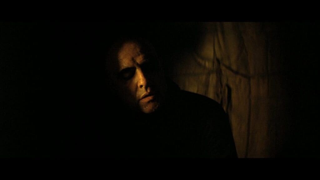 Marlon Brando como el coronel Kurtz en Apocalypse Now (1979), iluminado parcialmente en la oscuridad