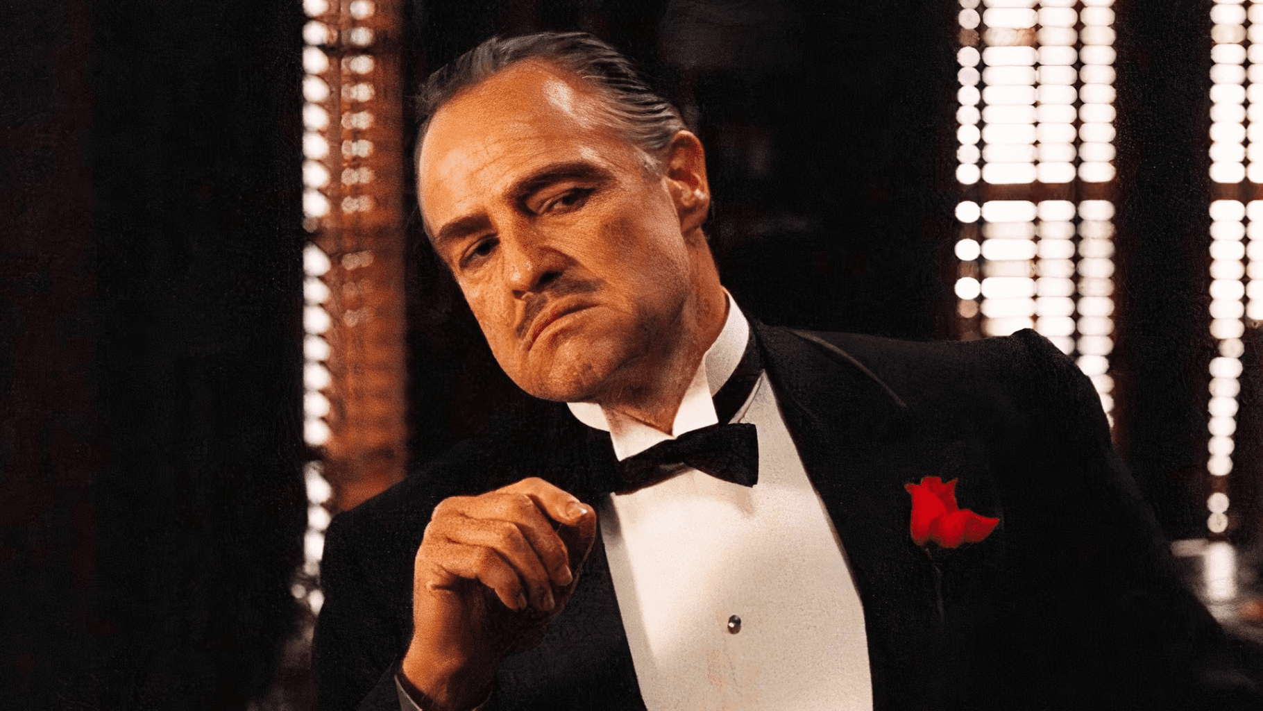 Marlon Brando como Vito Corleone en El Padrino (1972), con esmoquin y flor roja en el bolsillo