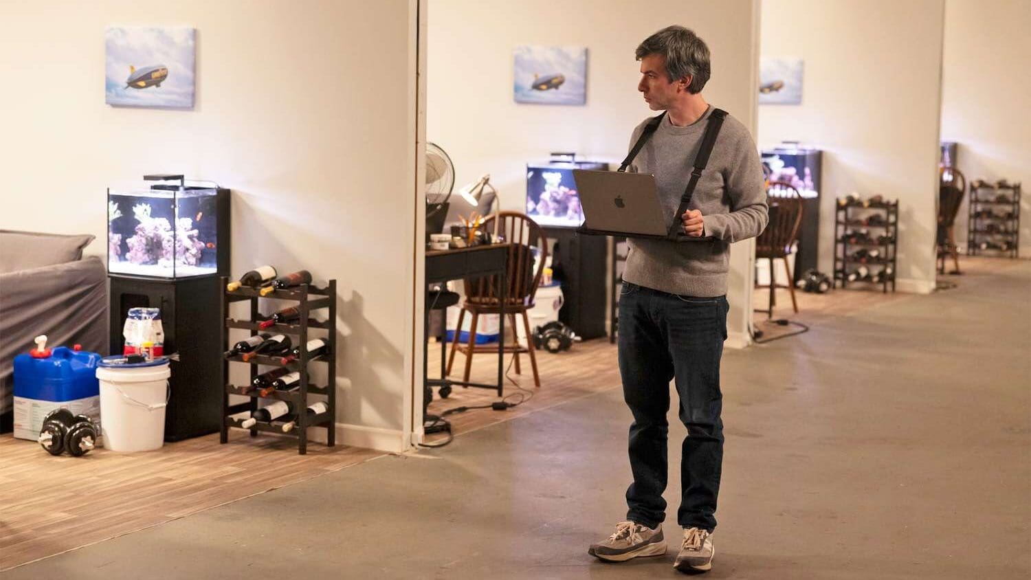 Nathan Fielder en un set recreado en The Rehearsal, usando una laptop colgada al pecho