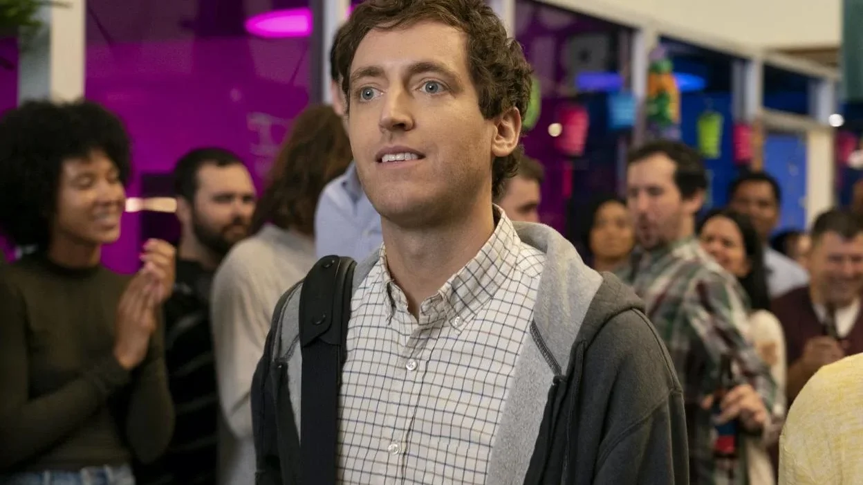 Thomas Middleditch como Richard Hendricks en Silicon Valley, rodeado de personas en una oficina de startup