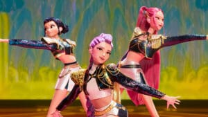 Las integrantes de Huntrix bailan en el escenario con trajes brillantes durante una presentación musical en la película animada K-Pop Demon Hunters (2025).