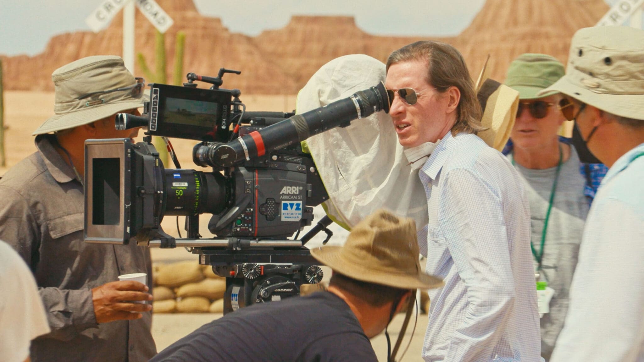 Wes Anderson filmando una escena de "Asteroid City" (2023) en el set, rodeado de su equipo técnico y utilizando una cámara ARRI.