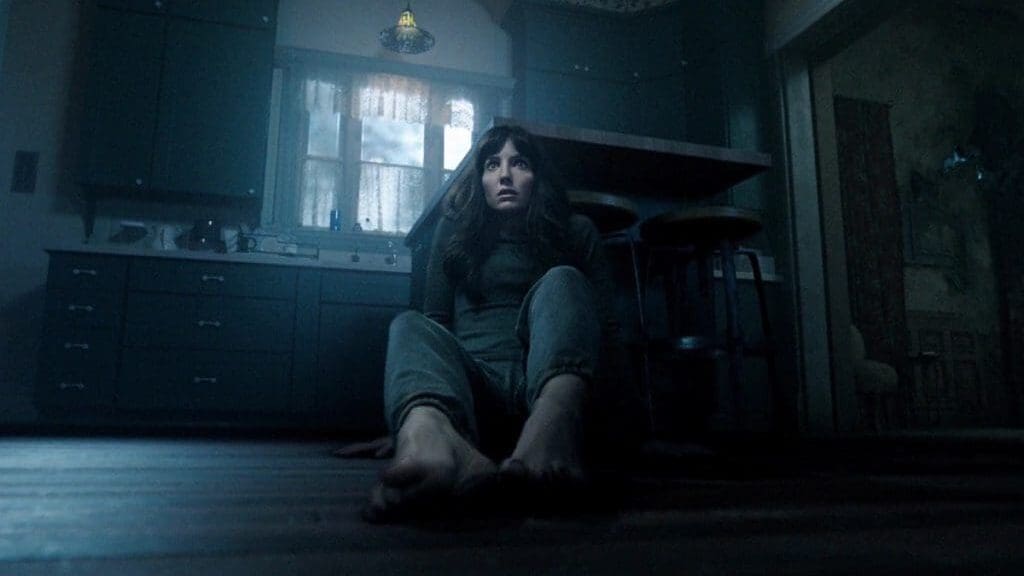 Madison (Annabelle Wallis) aterrorizada en el suelo de su casa en una escena clave de Maligno (2021), el thriller de terror dirigido por James Wan
