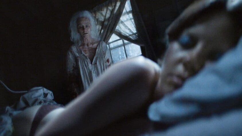 Escena de la película X (2022) de Ti West, donde Pearl observa a una joven dormida, en un inquietante momento del slasher protagonizado por Mia Goth