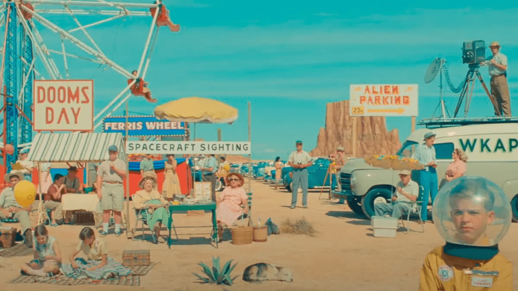 Escena del mercado en el desierto en "Asteroid City" (2023), con estética retro y referencias a OVNIs, dirigida por Wes Anderson.