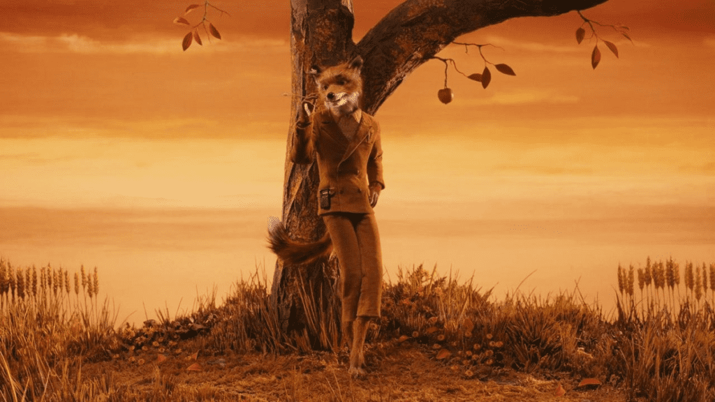 Mr. Fox apoyado contra un árbol en un paisaje otoñal en la película animada "Fantastic Mr. Fox" (2009) de Wes Anderson.