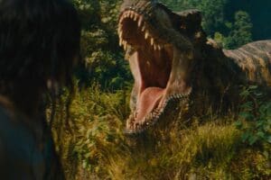 Dinosaurio rugiendo frente a un personaje en la selva en Jurassic World: Renace (2025)